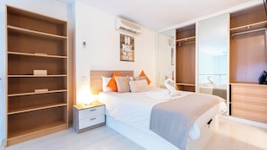 A modern bedroom with a large bed, built-in wardrobe, and a bedside table.