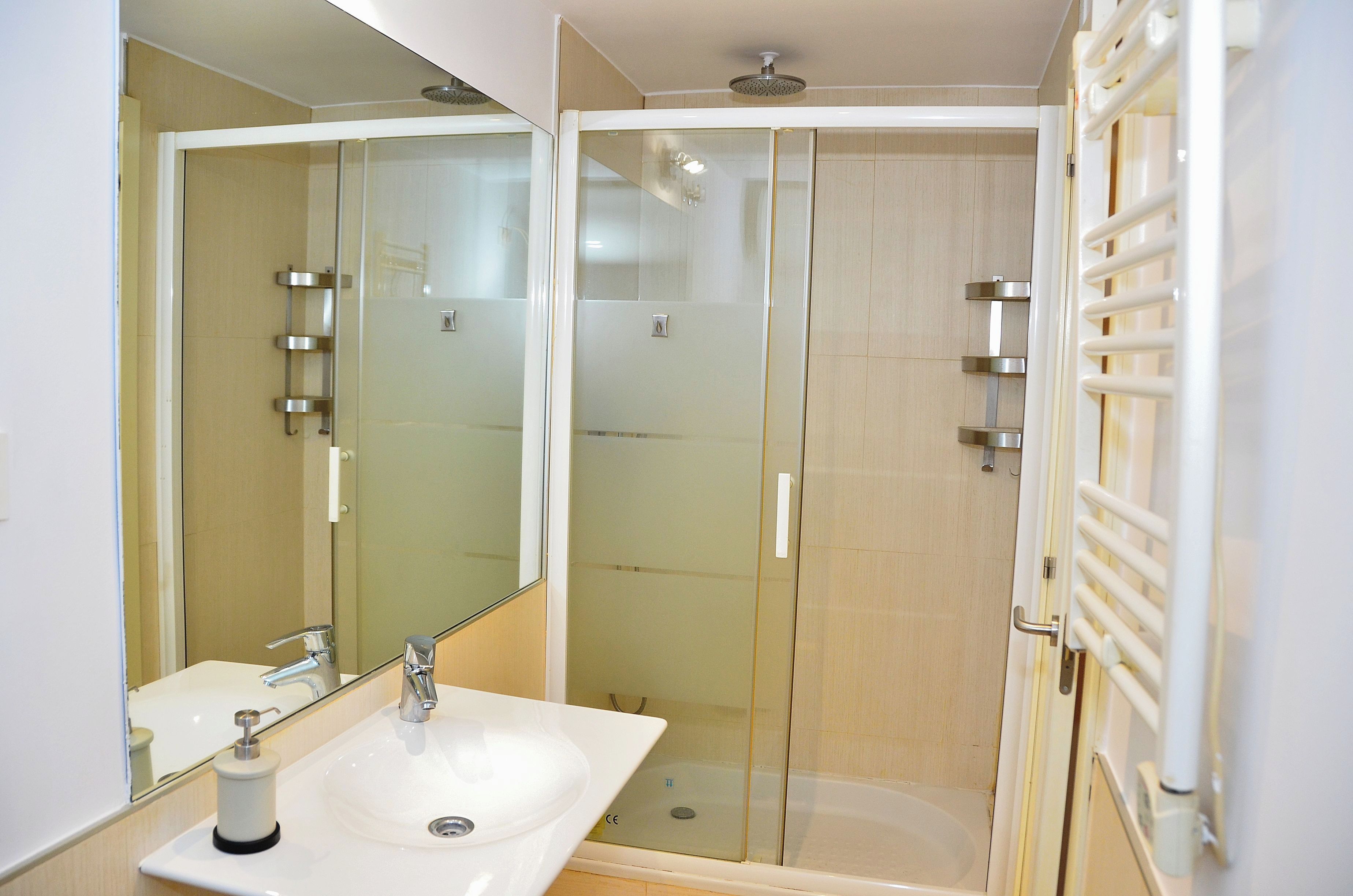 Une salle de bain moderne avec une douche à parois de verre, un lavabo blanc et un miroir.