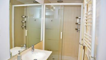 A modern bathroom with a glass-enclosed shower, a white sink, and a mirror.