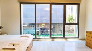 A bedroom with a large sliding glass door leading to a balcony with outdoor furniture.