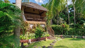 A two-story building with a balcony, surrounded by lush tropical vegetation and a stone pathway leading to the entrance. - A serene luxury villa in Berawa, Canggu! (Canggu)