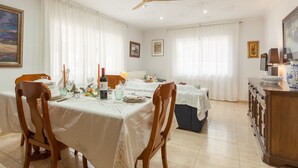 Comedor con mesa lista para cuatro, ventilador de techo y vista de la habitación.