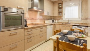 Una cocina moderna con electrodomésticos de acero inoxidable, armarios de madera y un comedor con una mesa lista para dos.