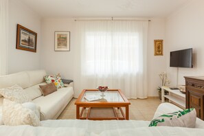 A living room with a sofa, coffee table, TV, and framed pictures on the walls. - Apartment 'Amelie' with Wi-Fi (Canet de Mar)