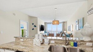 Una cocina moderna con una isla grande, un lavamanos de acero inoxidable y vistas al balcón.