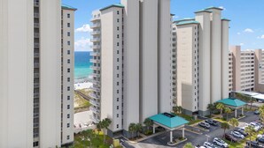 Un hotel de gran altura con varios pisos, un estacionamiento y vista a la playa.