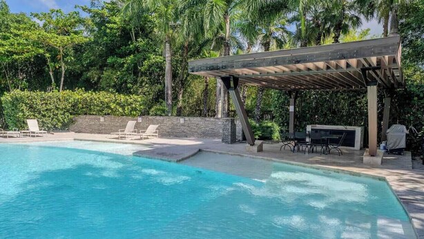 Ein Schwimmbecken mit Liegestühlen und einer überdachten Terrasse.