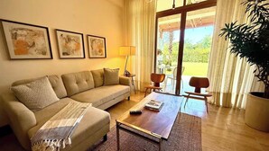 Ein Wohnzimmer mit einer Couch, einem Couchtisch und einem großen Fenster mit Vorhängen.