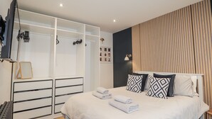 A bedroom with a bed, a wardrobe, a mirror, and a wall-mounted TV. - Apple Tree Cottage (Buckie)