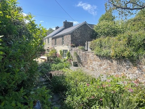 A stone house with a garden, a stone wall, and a clear blue sky. - Penally Mews (Cardigan)