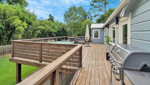 Eine Terrasse mit Pool, Gartenmöbeln und Grill.