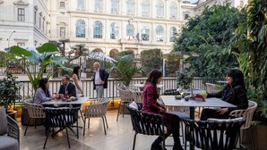 An outdoor café with tables and chairs, surrounded by greenery and a historic building in the background. - Hotiday Roma Trevi (Rome)