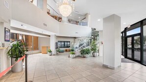 A spacious lobby with a staircase, potted plants, and a chandelier. - Cozy 1-Bedroom Oceanfront Condo in Myrtle Beach (Myrtle Beach)