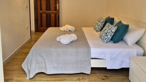 Une chambre d’hôtel avec un lit, une table de chevet, une porte en bois et un climatiseur fixé au mur.