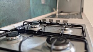 Une cuisine équipée d’une cuisinière à gaz, d’une hotte en acier inoxydable et d’un crédence moderne.