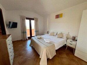 Een hotelkamer met een bed, een televisie, een bureau en een stoel.