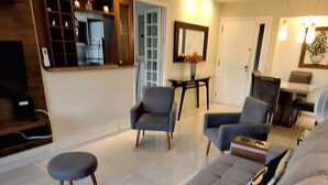 Una sala de estar moderna con un sofá grande, dos sillones, una mesita y un televisor.