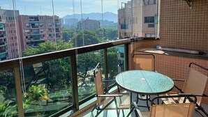 Un balcón con cerramiento de vidrio, una mesa redonda y sillas.