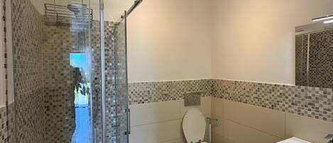 Ein modernes Badezimmer mit einer gläsernen Dusche, einer Toilette und einem Waschbecken.