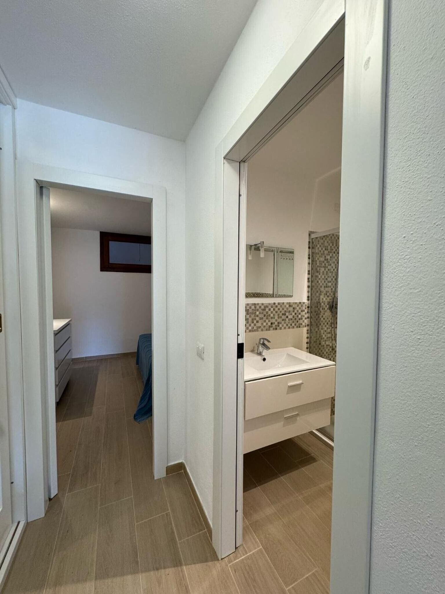 Ein Gang, der zu einem Badezimmer mit Waschbecken und Spiegel führt.