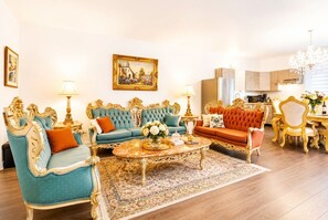A luxurious living room with ornate furniture, a coffee table, and a dining area with a chandelier.