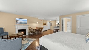 Une chambre d’hôtel avec une cheminée, un coin repas, une cuisine et un grand lit.