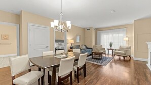 A spacious living room with a dining area, a chandelier, and a fireplace. - York Beach, Maine | Spacious Lock-Off Condo for Groups | Sleeps 8 (York)