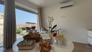 Ein Frühstücksbuffet mit Gebäck, Brot und Getränken auf einem Tisch im Hotelzimmer mit Blick.