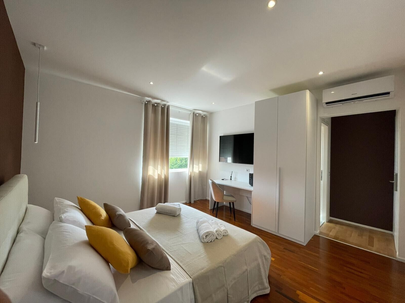 Ein modernes Hotelzimmer mit Bett, Schreibtisch, Fernseher und Klimaanlage.