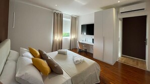 Une chambre d’hôtel moderne équipée d’un lit, d’un bureau, d’une télévision et d’un système de climatisation.