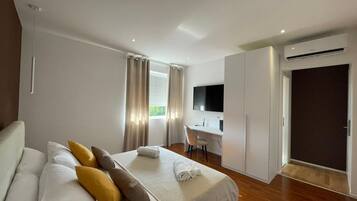Ein modernes Hotelzimmer mit Bett, Schreibtisch, Fernseher und Klimaanlage.