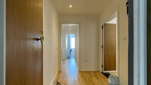 Un couloir avec un plancher en bois, une porte à gauche et une porte à droite.