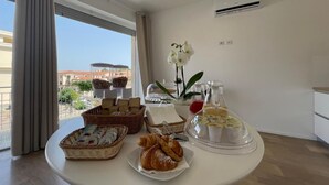 Un bufé de desayuno con pasteles, pan y bebidas sobre una mesa en una habitación de hotel con vistas.