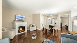 A living room with a fireplace, a television, and a dining area with chairs and a table. - Big-Group Lock-Off Condo | 1BR + Resort Room | Sleeps a Crowd (York)