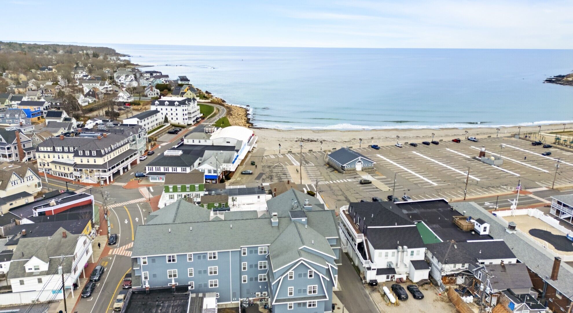 A coastal town with a beach, parking lot, and various buildings including a large hotel.