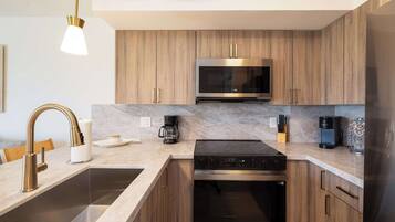 A modern kitchen with wooden cabinets, a stainless steel range, a built-in oven, a coffee maker, and a microwave.