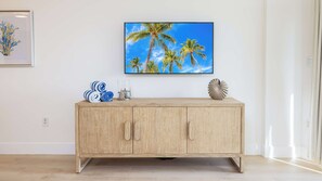 Un meuble en bois surmonté d’un téléviseur qui diffuse une scène de paysage tropical.