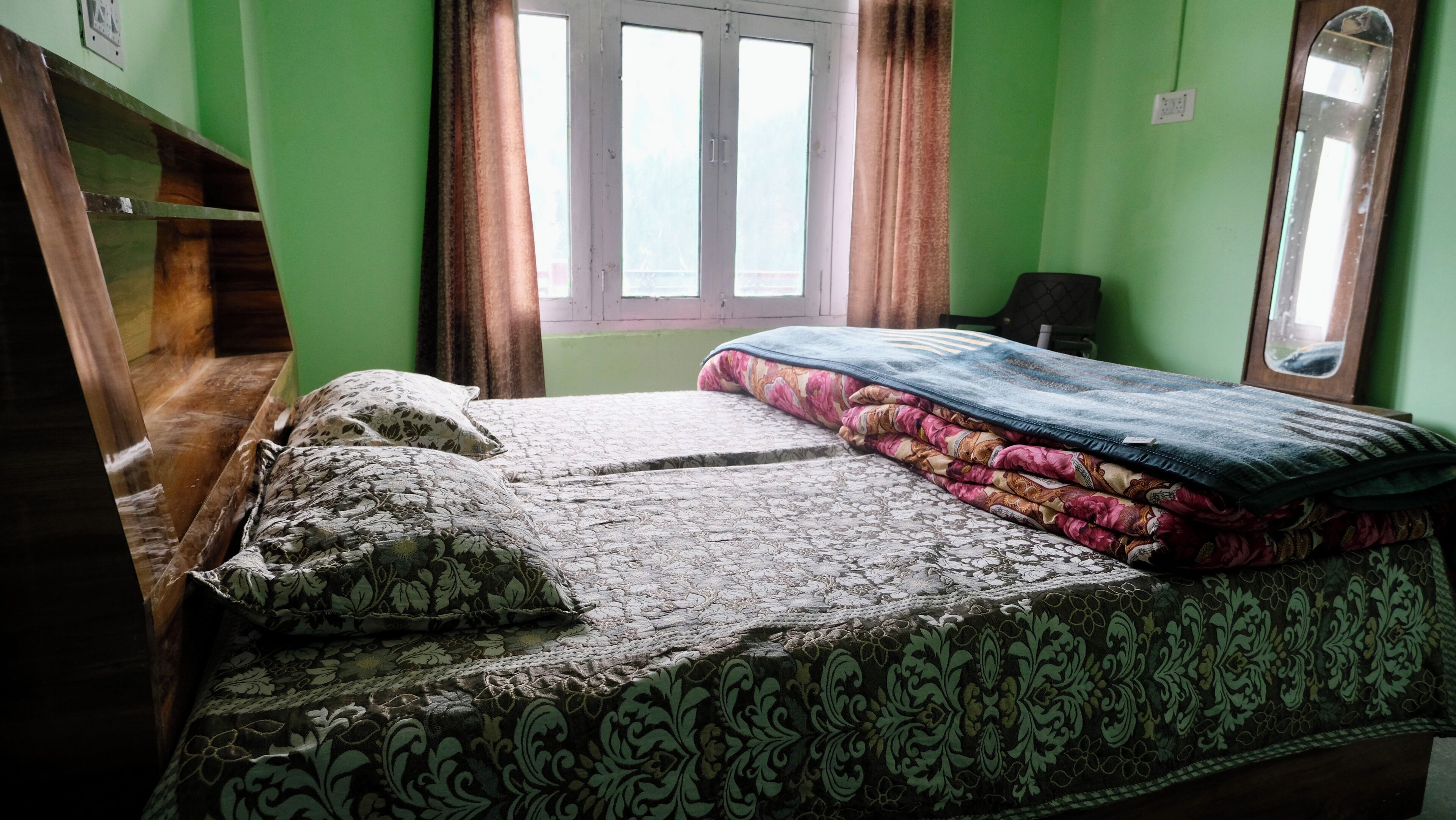A bedroom with a bed, pillows, a window, and a mirror.