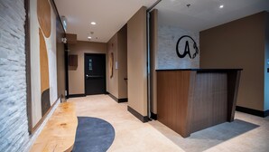 Un moderno vestíbulo de hotel con una recepción, un banco de madera y una pared de piedra.