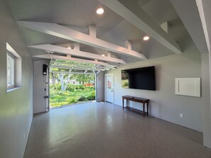 A modern interior with a garage door, a flat-screen TV, and a bench. - 4-bedroom house in Titletown (Ashwaubenon)