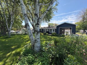 Ein Wohnhaus mit Garage, umgeben von üppigem Grün und Bäumen.