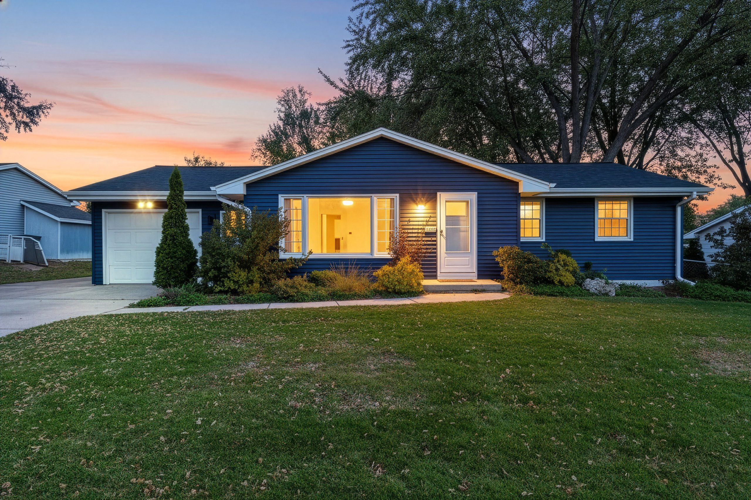 A two-story house with a garage, a front porch, and a well-maintained lawn.