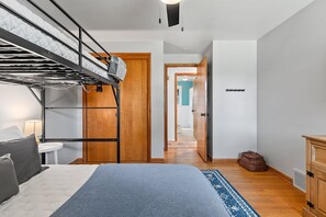 Une chambre avec des lits superposés, une petite table de chevet, une lampe et un tapis bleu.