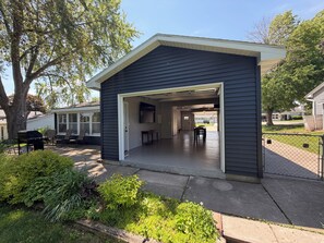 A garage with a TV mounted on the wall, a covered patio area, and a view of the street. - 4-bedroom house in Titletown (Ashwaubenon)