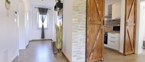 A modern interior with a wooden floor, a kitchen area with white cabinets, and a sliding barn-style door.