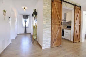 A modern interior with a wooden floor, a kitchen area with white cabinets, and a sliding barn-style door. - Relaxing Holiday Home With Shared Pool (Umag)