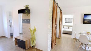 A modern living room with a sliding door, a dining area with white chairs, and a flat-screen TV mounted on the wall. - Relaxing Holiday Home With Shared Pool (Umag)