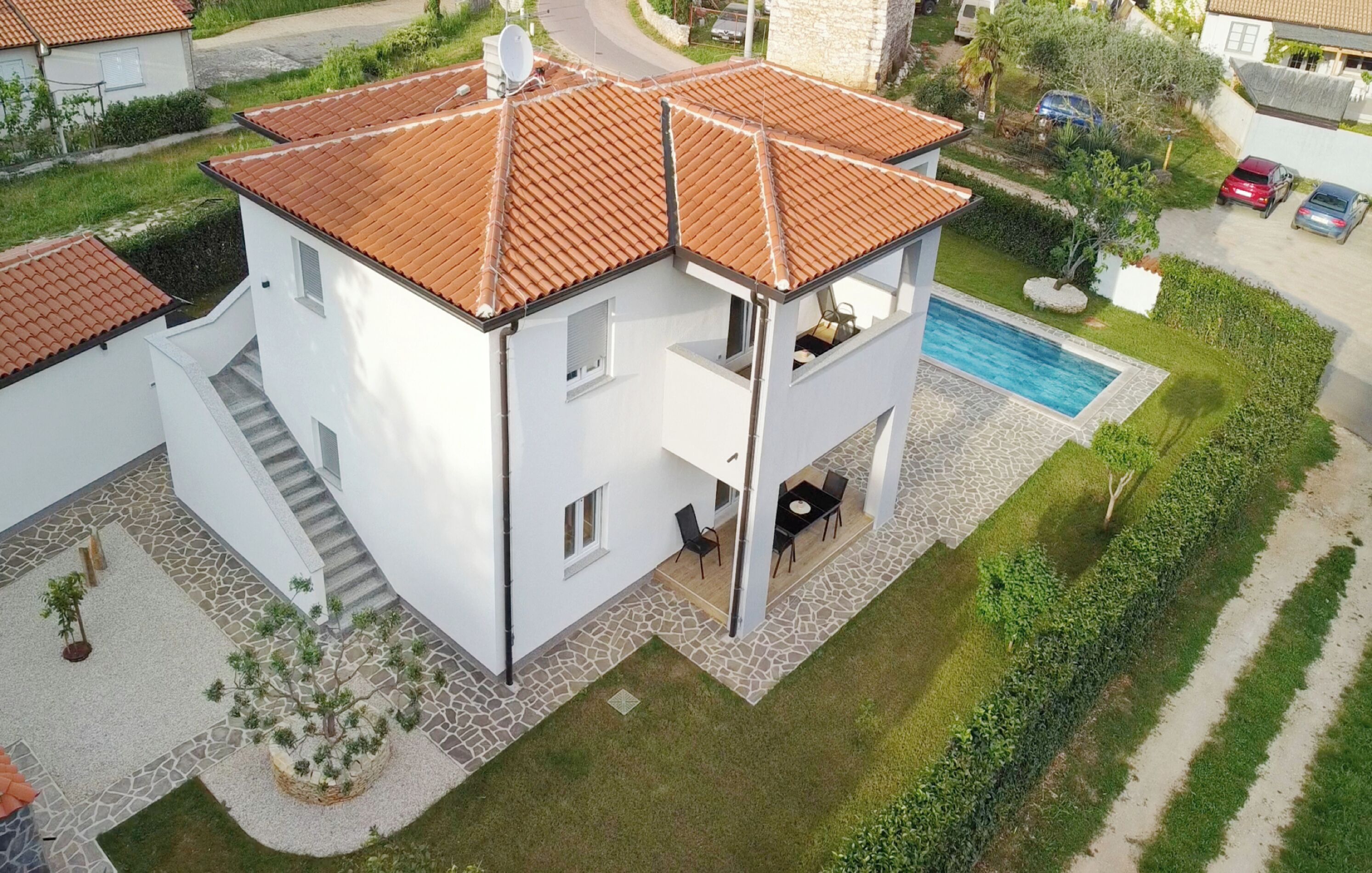 Une maison à deux étages, avec un toit en tuiles, une piscine et un espace patio.