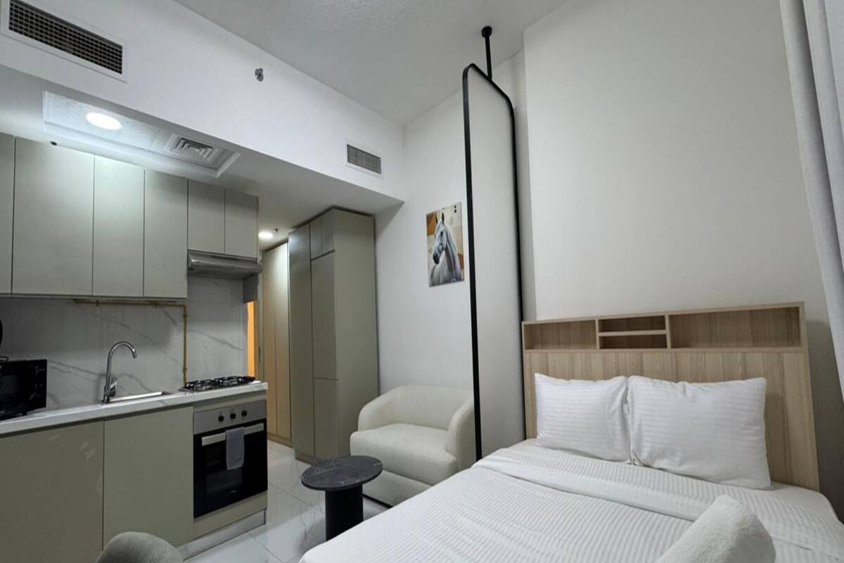 A hotel room with a bed, a small kitchen area, and a bathroom.