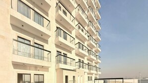 A modern hotel with a rooftop infinity pool, large windows, and a clean, minimalist design. - Luxury Apartment with Pool Gym & Free Parking at Equiti Gates Jebel Ali (Dubai)